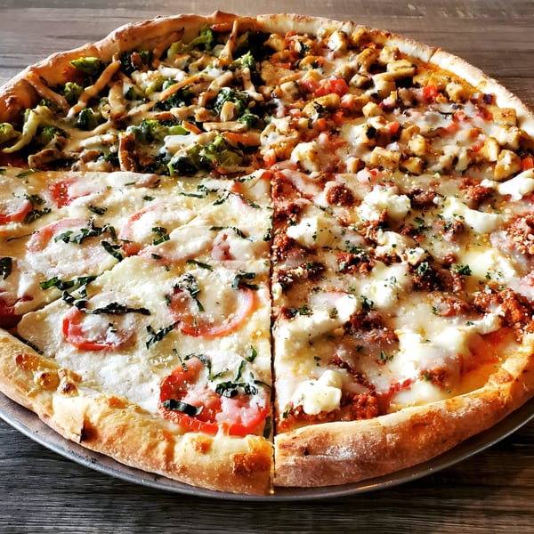 A large Piu Bello Buckhead pizza with four different toppings, including chicken, broccoli, and tomatoes.