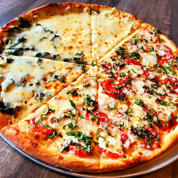 Piu Bello Buckhead's large pizza, half with white cheese and spinach, half with tomatoes and basil.